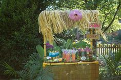 a tiki bar with lots of drinks on it in the middle of some trees