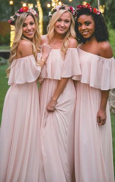 three women in pink dresses posing for the camera with flowers on their head and shoulders