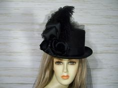 "All Black costume style hard felt black top hat with black ostrich plumes flowers and black tulle bustle and train. If you don't want the train just let me know and I can make one without the train. These run about 22.5\" for the inside circumference. If you need some hat sizer let me know and I can add it to your package. This top hat would be perfect for any outfit from Halloween, Kentucky derby, Victorian, Steampunk to Gothic events. Check out my other hats and fascinators. https://www.etsy. White Derby Hat, All Black Costumes, Steampunk Top, Steampunk Top Hat, Mad Hat, Black Top Hat, Costume Noir, Halloween Top, Black Costume