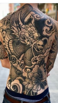 the back of a man's body with tattoos on his chest and arms,