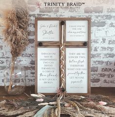 two wooden signs sitting on top of a table next to dried flowers and feathers in vases