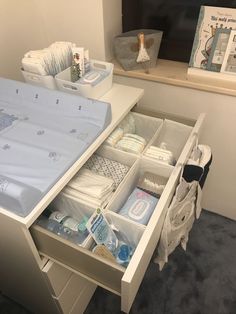 an open drawer in the middle of a desk with baby items inside and on it