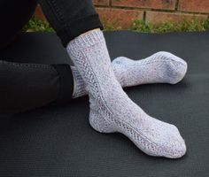 a person sitting on the ground with their feet up wearing socks that have been knitted