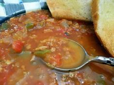 a spoon full of soup with bread on the side