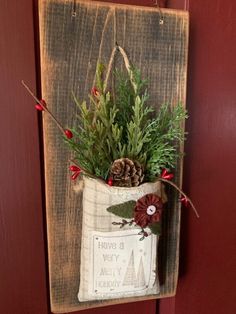 a christmas decoration hanging on a red door with pine cones and evergreens in a burlock