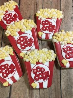 four red and white cookies shaped like popcorns with the word boo on them sitting on a wooden table