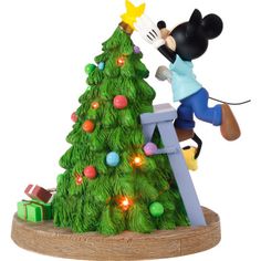 a mickey mouse figurine is decorating a christmas tree with lights on it