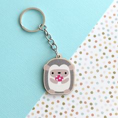 a monkey keychain with a pink bubble in it's mouth on a polka dot background