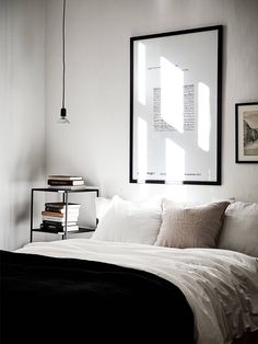 a bed with white sheets and pillows next to a framed photograph on the wall above it