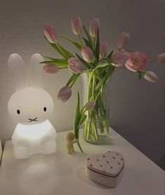 a white bunny lamp sitting next to a vase with pink flowers