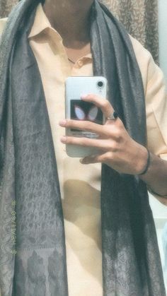 a woman taking a selfie in front of a mirror wearing a scarf and holding a cell phone