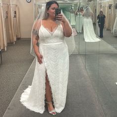 a woman taking a selfie in front of a mirror wearing a white wedding dress