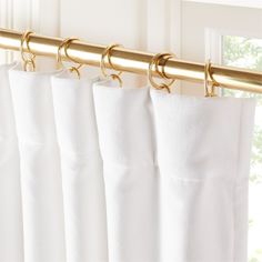 white curtains with gold hardware hanging on a rod