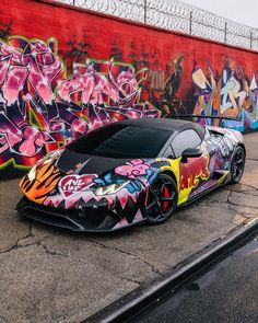 a very nice looking car parked in front of some graffiti covered walls and fenced area