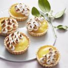 small pies with meringue and whipped cream on top sit on a white plate