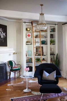 a living room filled with furniture and a chandelier hanging from the ceiling over a fireplace