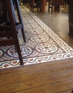 a wooden floor with an ornate pattern on it and several stools in the background