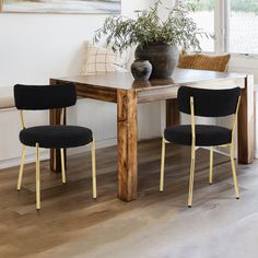 a dining room table with two chairs and a potted plant