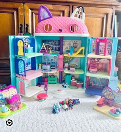 there is a doll house with lots of toys in the room and on the floor