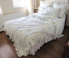 the bed is made up with white sheets and ruffled bedspread on it