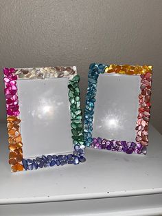 there are three different colored glass frames on the counter top, one is empty and the other has small stones in it