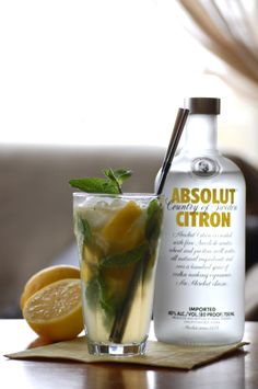 a bottle of absolut citron next to a glass filled with lemonade