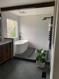 a bathroom with black and white tile flooring and a large tub in the corner