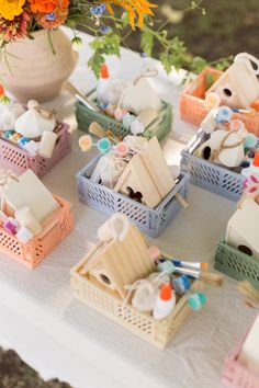 there are many small baskets on the table with flowers in them, and one is filled with doll houses