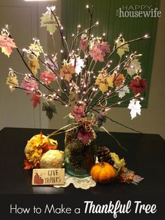 a vase filled with leaves and pumpkins sitting on top of a table next to a sign that says, how to make a thanksgiving tree