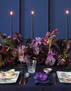 the table is set with purple flowers and candles