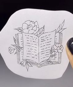 a computer mouse pad with a drawing of an open book and flowers on the front