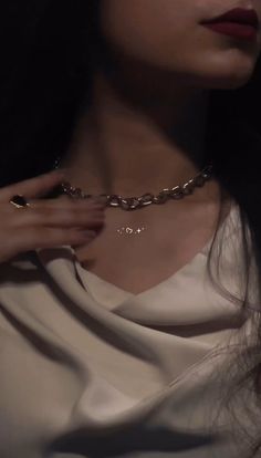 a close up of a person wearing a necklace and holding onto her hand with the other hand