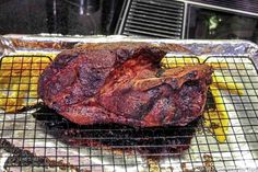 a large piece of meat sitting on top of a metal grill grate next to some bananas