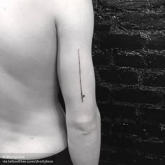 a black and white photo of a man's arm with a small tattoo on it