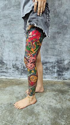 a person with tattoos on their legs and leggings, standing in front of a wall