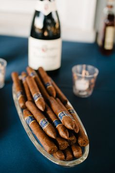 cigars are arranged on a table next to a bottle of wine and shot glasses