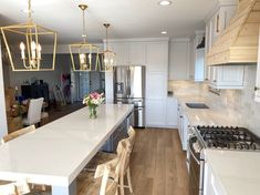 a kitchen with white cabinets and marble counter tops, an island in the middle is surrounded by chairs