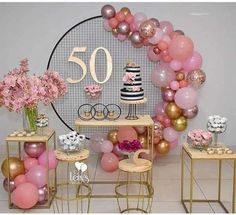 a table topped with lots of pink and gold balloons