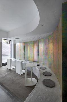 a room with several tables and stools in front of colorful paintings on the wall