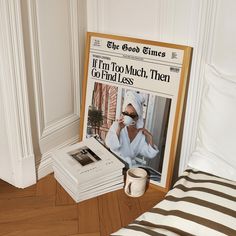 a stack of newspapers sitting on top of a wooden floor next to a cup of coffee