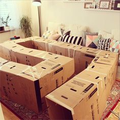 several boxes stacked on top of each other in front of a couch with pillows around it