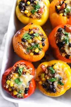 several stuffed bell peppers with black beans, corn and cilantro in a baking dish