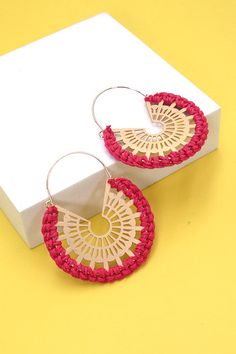 a pair of red and white earrings sitting on top of a yellow table next to a box