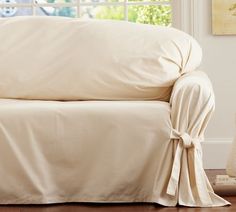 a couch covered with a white cover in front of a window