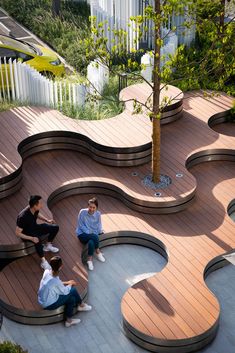 three people sitting on benches near a tree