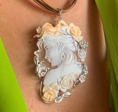 Crafted with meticulous care and artistry, the Hand-Carved Cameo Necklace for women embodies elegance and sophistication. This exquisite piece, skillfully handmade in Italy, showcases a delicate cameo of a nymph, exuding a timeless charm that captivates effortlessly. Whether as a thoughtful wedding gift or a gesture of appreciation for a special woman, this necklace is a symbol of refined taste and creativity. The intricate detailing and the superior craftsmanship make it a standout accessory th Luxury Cameo Pendant Jewelry, Elegant Round Pendant Intaglio Necklace, Exquisite Formal Necklace With Large Pendant, Elegant Carved Oval Jewelry, Elegant Oval Carved Jewelry, Custom Hallmarked Necklace For Formal Occasions, Exquisite Oval Necklace With Large Pendant, Formal Custom Hallmarked Necklace, Elegant Carved Necklaces For Formal Occasions