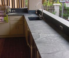 an outdoor kitchen with granite counter tops and tile flooring is pictured in this image