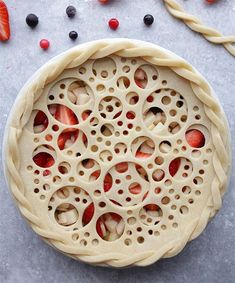 an uncooked pie sitting on top of a table next to berries and strawberries