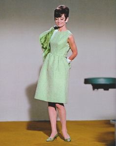 a woman in a green dress standing on a wooden floor