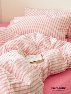 pink and white striped bedding with a book on the pillowcase in front of it